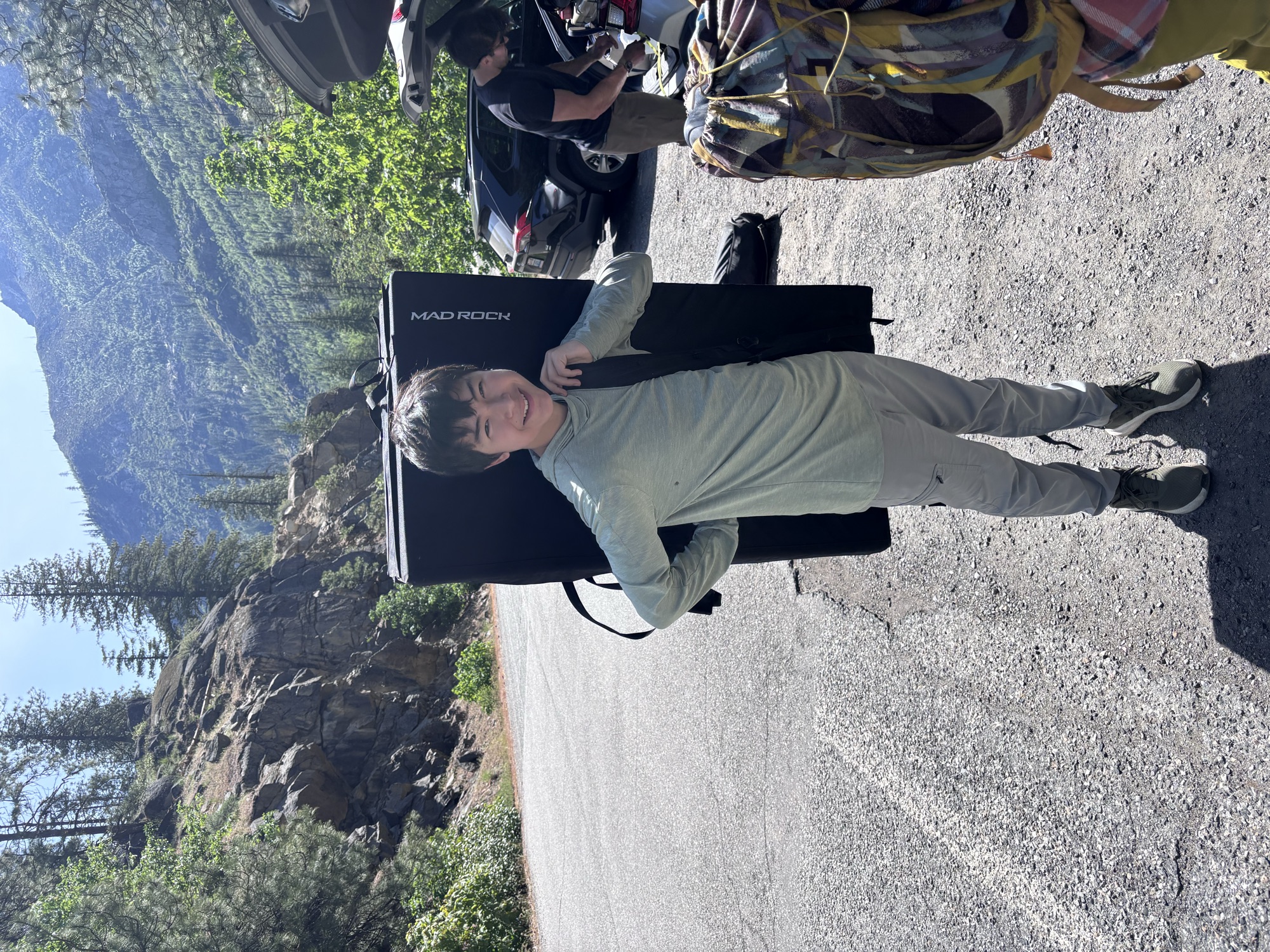 Kai carrying a crash pad on a mountain road