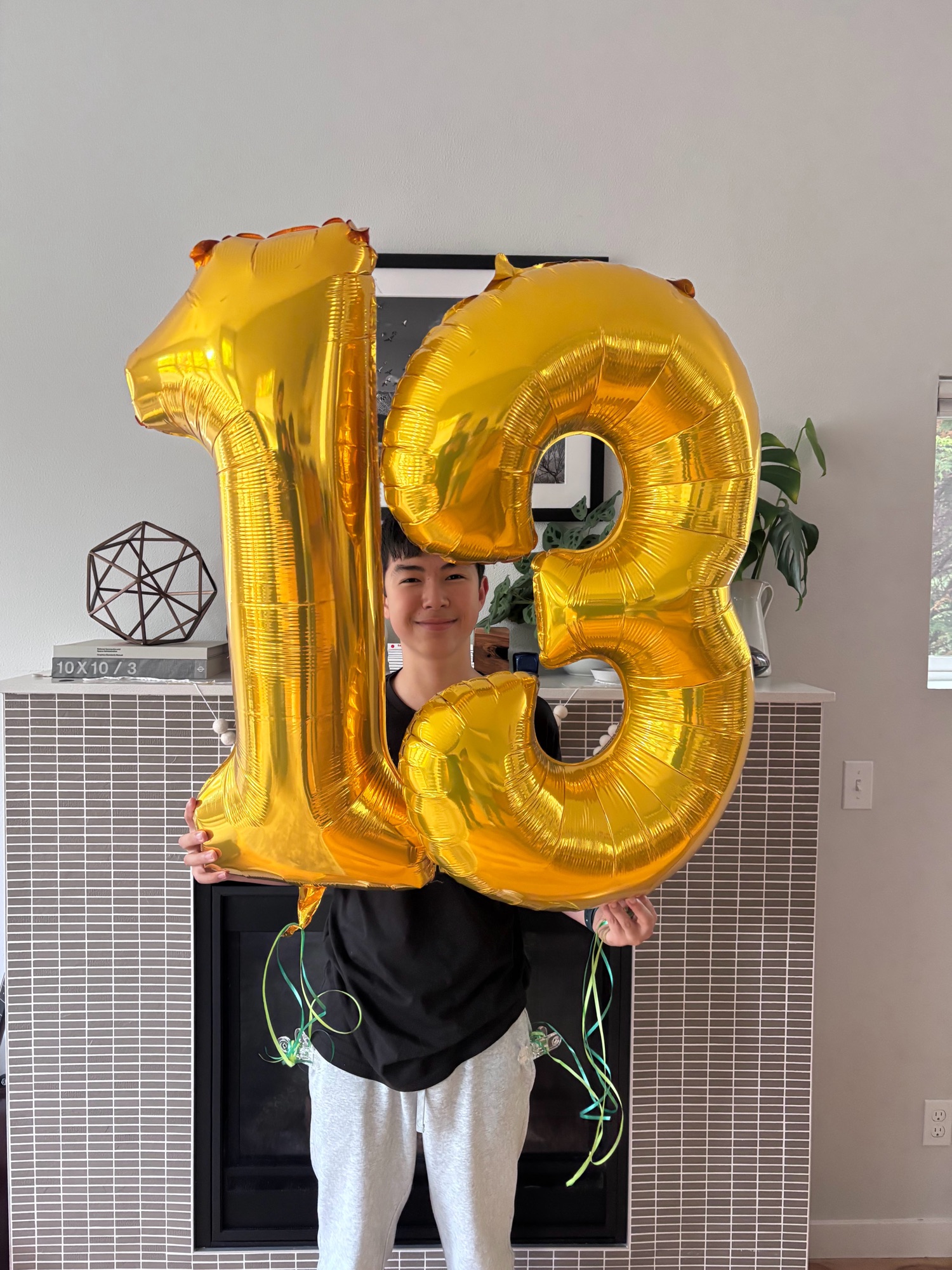 Kai holding 13 balloons on his birthday