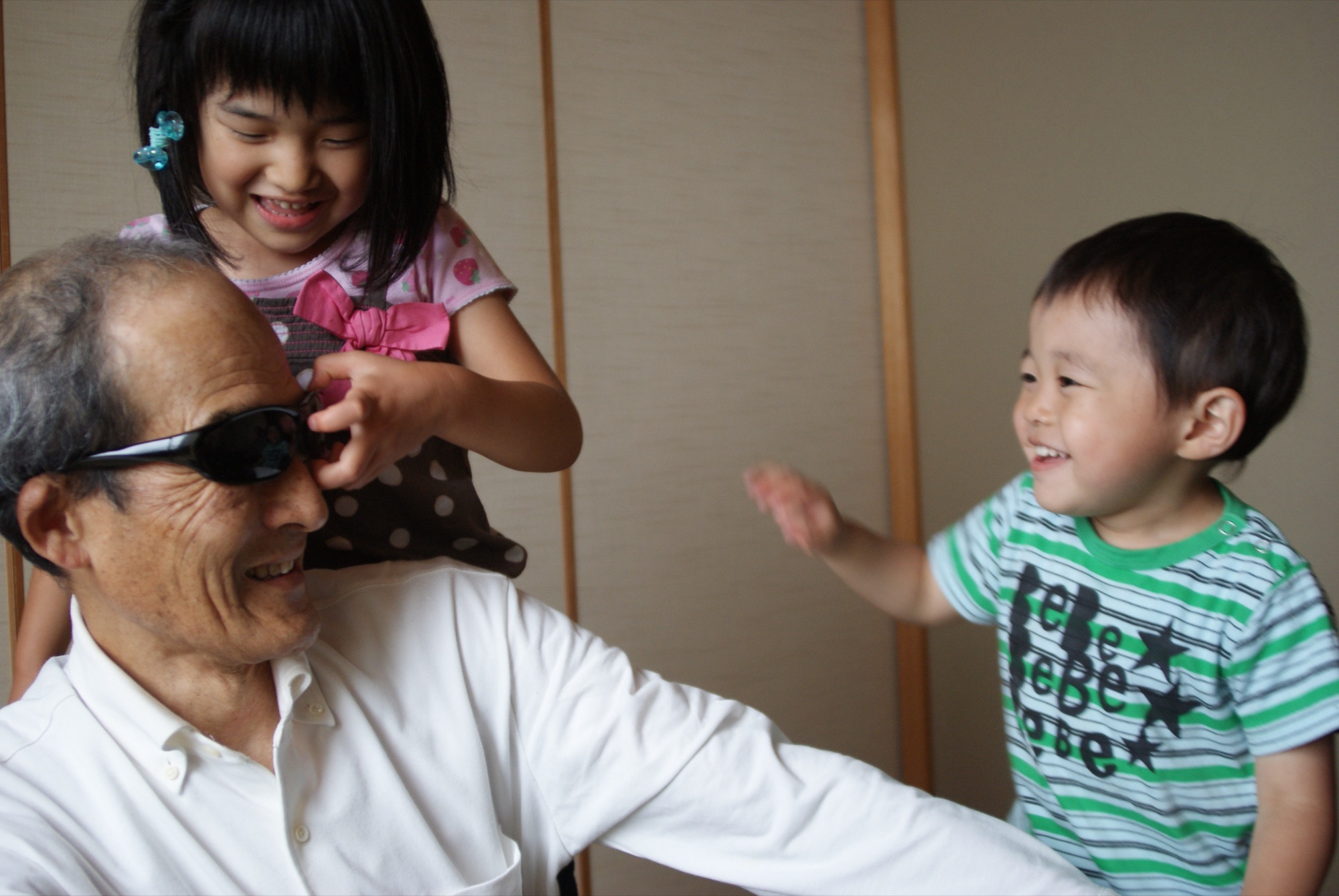 Jiji in sunglasses, laughing with Mia and Kai