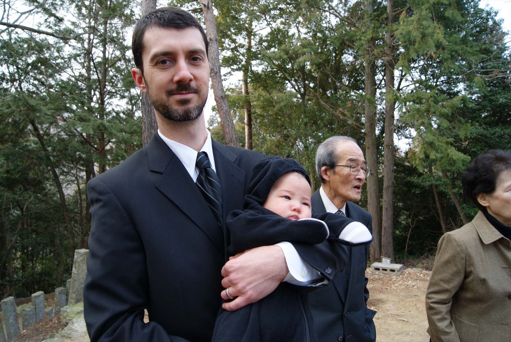 Luke holding baby Kai, with Itazu-san behind