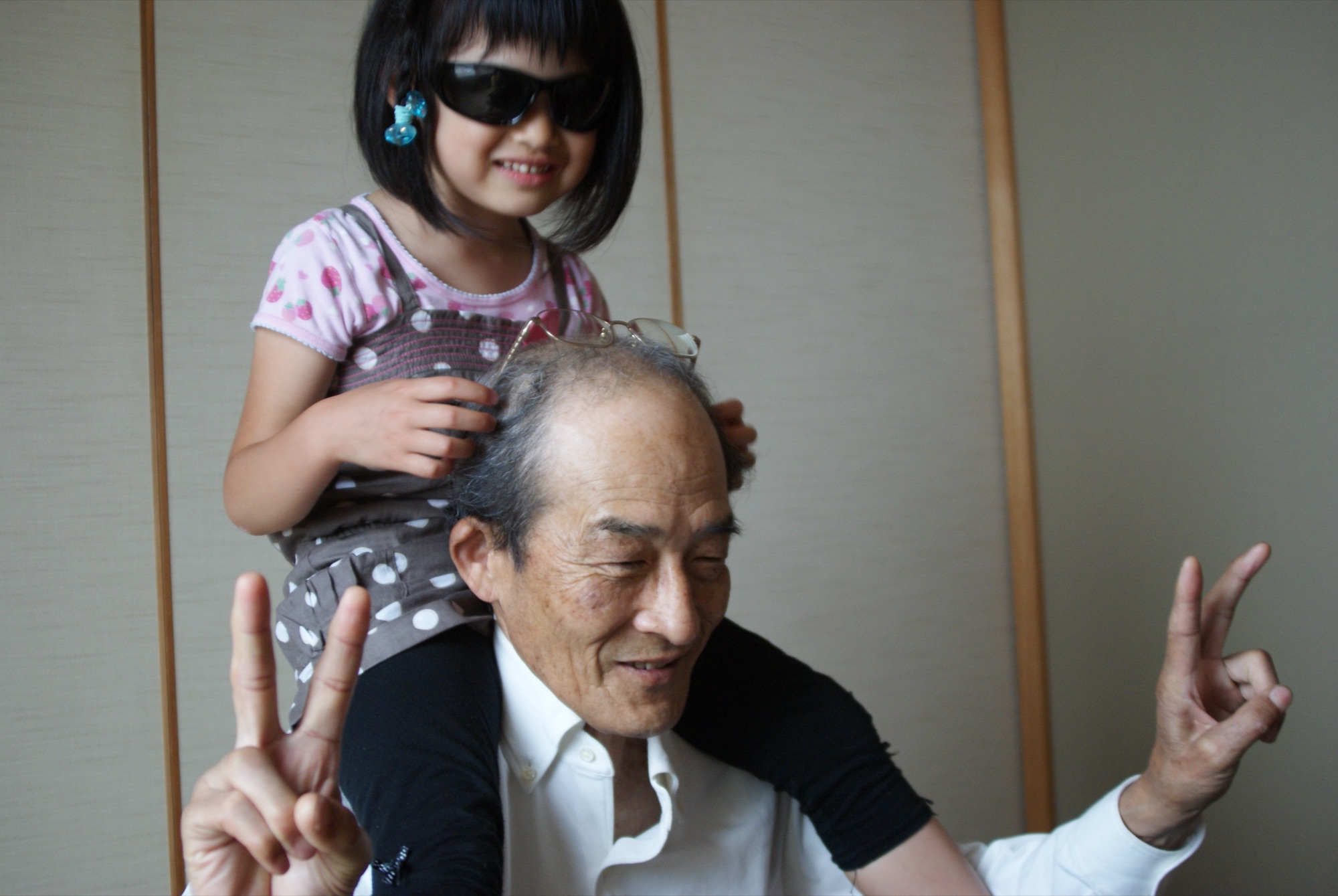 Mia in sunglasses on Jiji's shoulders, both making peace signs